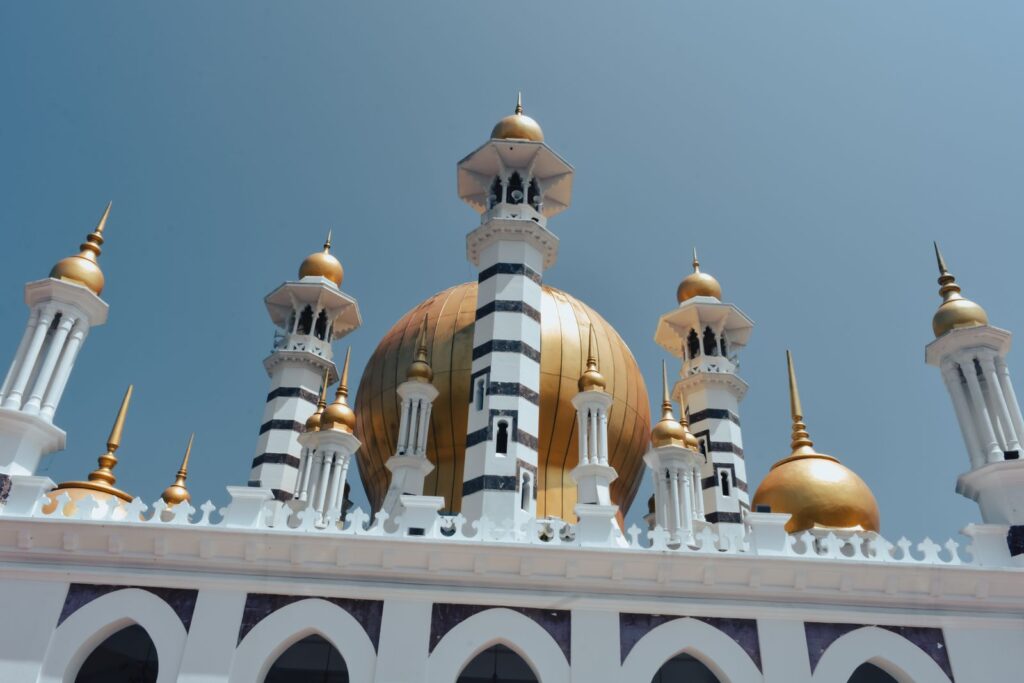 A stunning view of the Ubudiah Mosque's golden domes and minarets against a clear blue sky in Kuala Kangsar, Malaysia.