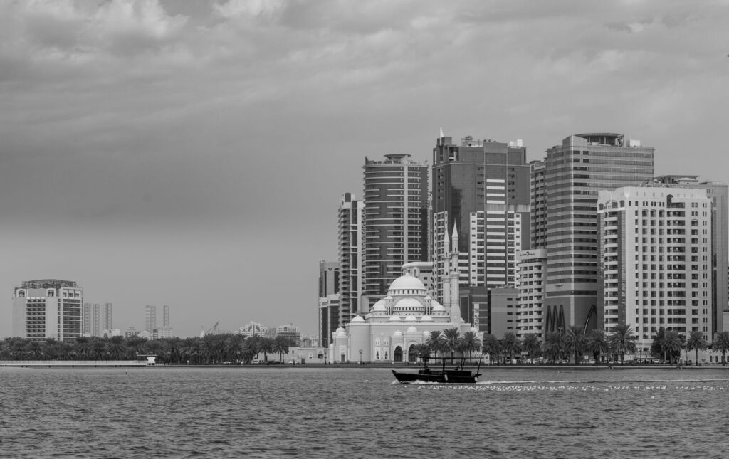 Black and white view of Sharjah skyline featuring Al Noor Mosque by the waterfront.